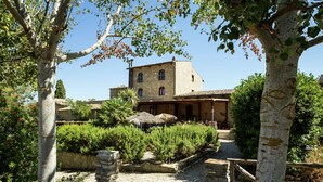 A stone building with a tiled roof, surrounded by lush greenery and a cobblestone pathway. - Charming Countryside Stay (Petralia Sottana)