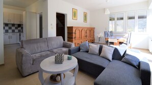 Uma sala de estar moderna com um sofá cinzento, uma mesa de centro redonda e um armário de madeira.