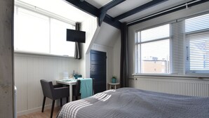 Un dormitorio con cama, escritorio, silla y televisión.