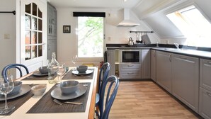 A modern kitchen with a dining area, featuring a large window, built-in cabinets, and a central island. - Modern Holiday Home in Wolphaartsdijk with Private Garden (Wolphaartsdijk)