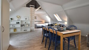 A spacious attic bedroom with a lofted dining area, wooden floor, and a white color scheme. - Modern Holiday Home in Wolphaartsdijk with Private Garden (Wolphaartsdijk)