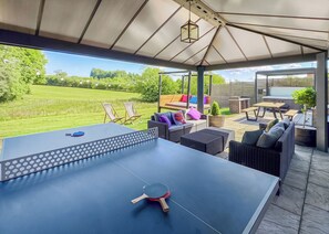 Ein Tischtennis-Tisch mit Sitzgelegenheiten und Blick auf eine grüne Landschaft.
