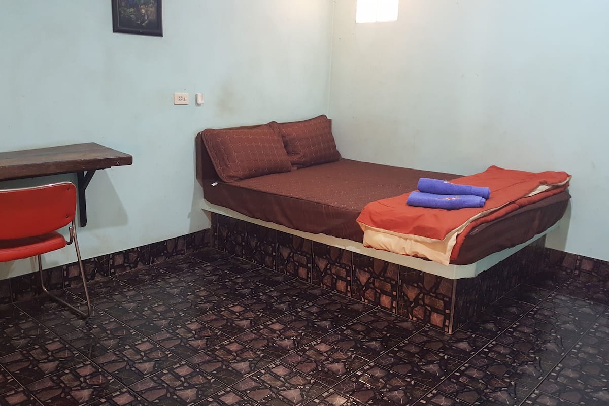 A small room with a bed, a desk, and a chair.