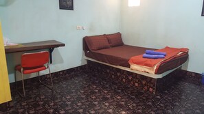A small room with a bed, a desk, and a chair. - Chok Amorn Resort (Ban Dung)