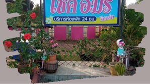 Ein Schild mit thailändischem Text, ein Blumentopf und eine Zierfigur.