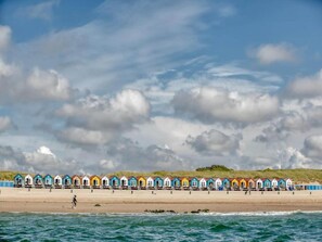A row of colorful beach huts along a sandy beach with a view of the sea and a cloudy sky. - Apartment in Vlissingen near Sandy Beach (Vlissingen)