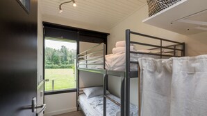 Habitación con literas y vista a un campo verde a través de una ventana.