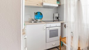 Eine kleine Küchenzeile mit Spüle, Kaffeemaschine und kleinem Backofen.