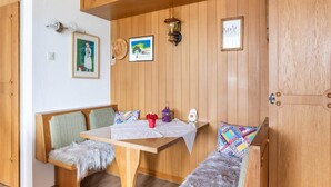 Ein gemütliches Zimmer mit einer hölzernen Bank, einem kleinen Tisch und einer Holztür.