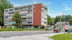 Ein mehrstöckiges Gebäude mit roter Fassade, wahrscheinlich Wohn- oder gemischtgenutztes Objekt.