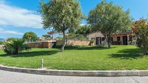 A residential property with a stone wall, a grassy lawn, and a house with a tiled roof. - Villa with private pool in a privileged environment. Wifi, A/c & lovely BBQ (Alcúdia)