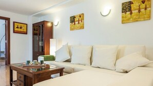 A hotel room with a sofa, a wooden cabinet, and artwork on the walls. - Villa with private pool in a privileged environment. Wifi, A/c & lovely BBQ (Alcúdia)
