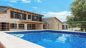 A swimming pool adjacent to a two-story building with large windows and a tiled roof. - Villa with private pool in a privileged environment. Wifi, A/c & lovely BBQ (Alcúdia)