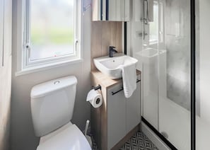 A compact bathroom with a toilet, sink, and shower.