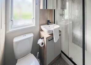 A compact bathroom with a toilet, sink, and shower.
