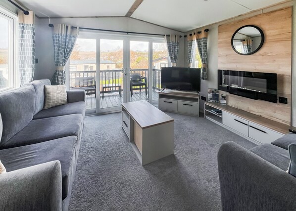A modern living room with a sofa, TV, and a balcony with sliding doors.