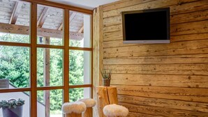 Quarto com paredes de madeira, uma janela grande e uma televisão de tela plana presa na parede.