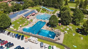 Vista aérea de um resort com várias piscinas, estacionamento e vegetação ao redor.