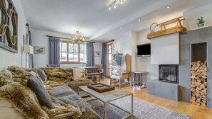 Uma sala de estar moderna com um amplo sofá modular, uma lareira e uma televisão montada na parede.