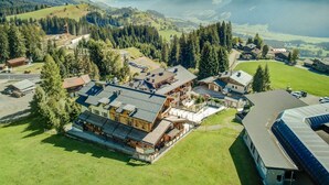 Um hotel de montanha com vários edifícios, área de estacionamento e vista para montanhas ao redor.