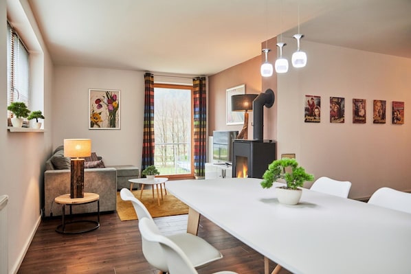 A modern living room with a fireplace, a dining table, and a sofa.