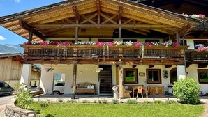 Een houten chalet met een balkon vol bloemen, een overdekte ingang en een kleine tuin.