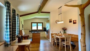 Een moderne keuken met houten vloeren, een eethoek met een houten tafel en stoelen, en een groot raam.