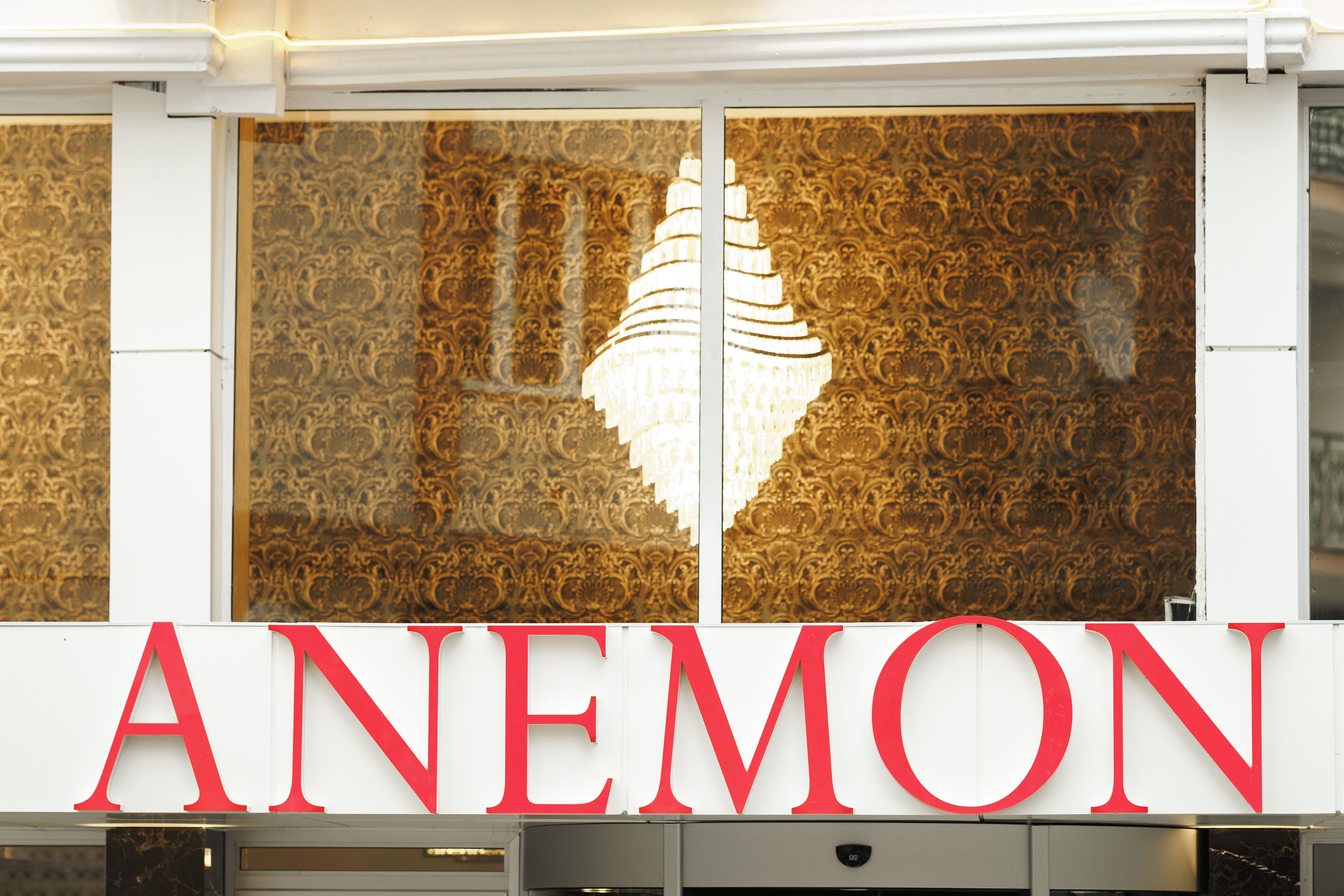 A hotel sign with the name 'ANEMON' in large red letters.