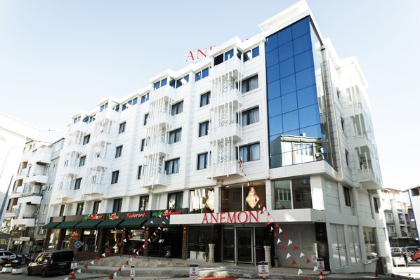 A multi-story hotel with a prominent 'ANEMON' sign at the ground level, featuring a modern facade with balconies and large windows.