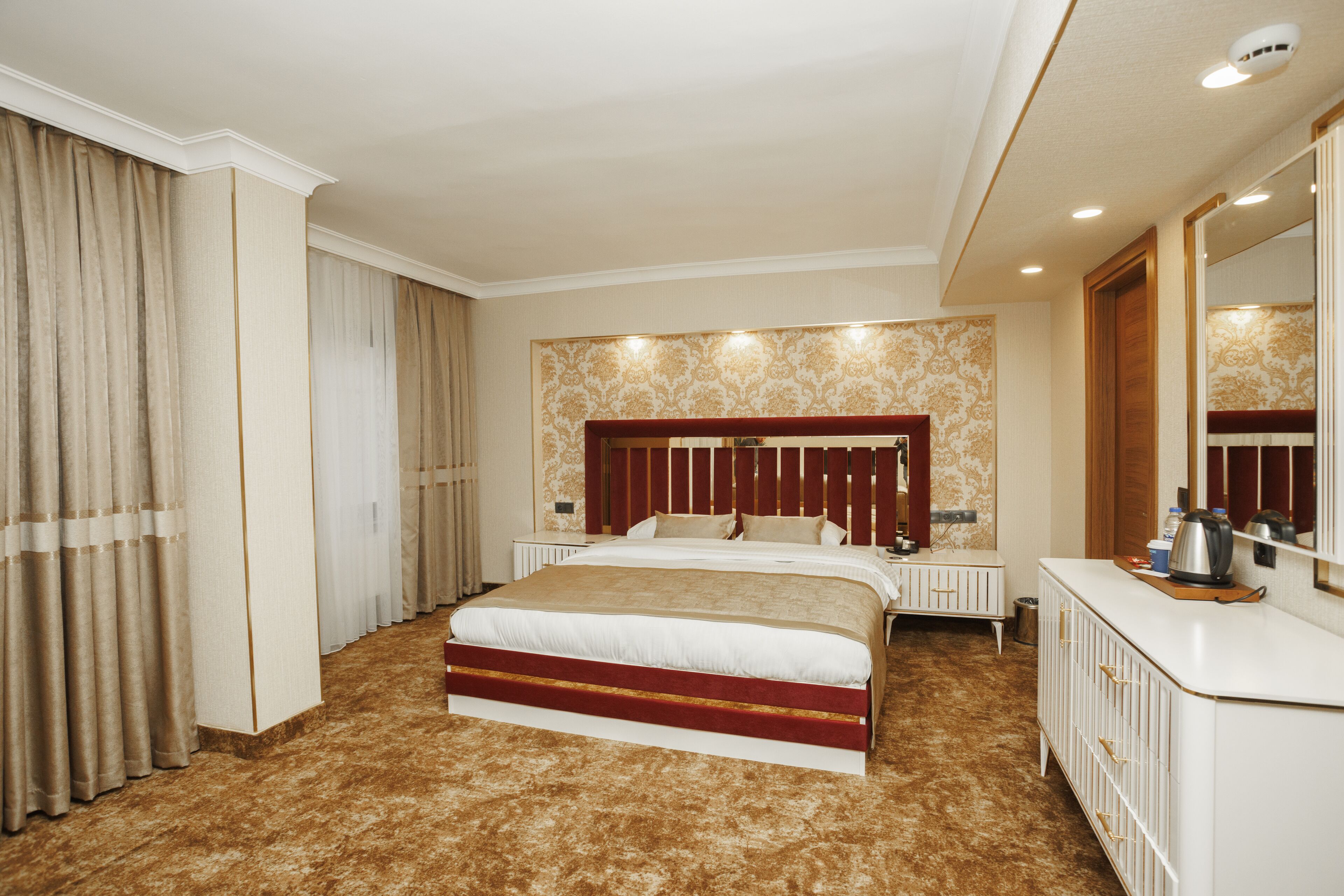 A hotel room with a large bed, a dresser, a mirror, and a radiator.