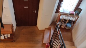 A staircase with a metal railing, a wooden floor, and a door in the background. - Ostello Sociale Borgo Venno (Lavenone)