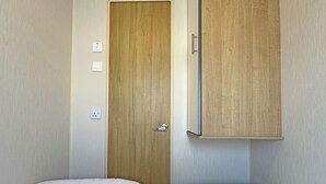 Huone, jossa on kaksi erillistä sänkyä, puuovi ja vetimellä varustettu vaatekaappi.