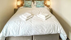 A neatly made bed with white linens and two folded towels, flanked by two bedside lamps and matching pillows. - Cedar Boutique Lodge (Aughton)