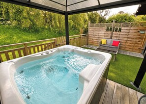 A hot tub in a covered outdoor area with a wooden deck, a wooden fence, and a garden. - 1 bedroom accommodation in Raywell, Beverley (Raywell, Beverley)
