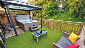 Un jardin avec un jacuzzi, du mobilier d’extérieur et un patio couvert.