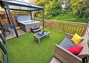 A backyard with a hot tub, outdoor furniture, and a covered patio area.