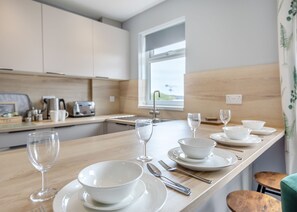 A modern kitchen with a wooden countertop, white appliances, and a window providing natural light.