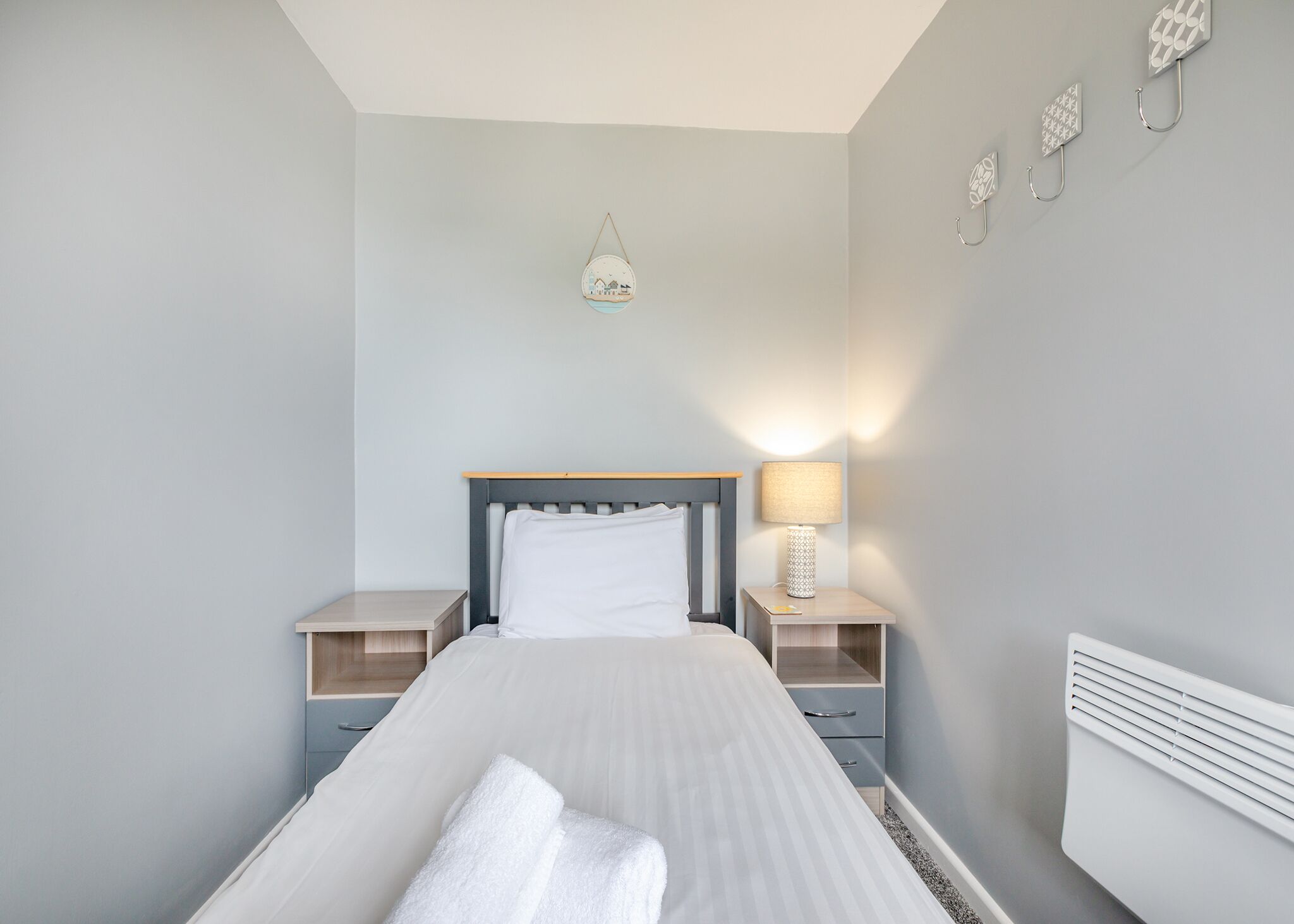 A bedroom with a bed, bedside tables, a lamp, and wall decorations.