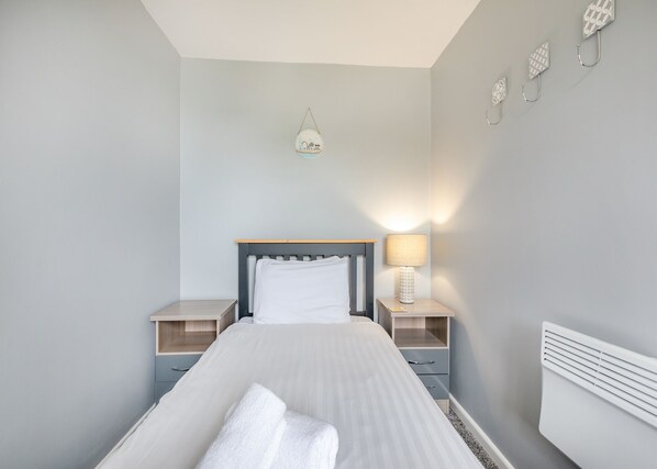 Une chambre à coucher avec un lit, des tables de chevet, une lampe et des éléments décoratifs sur les murs.