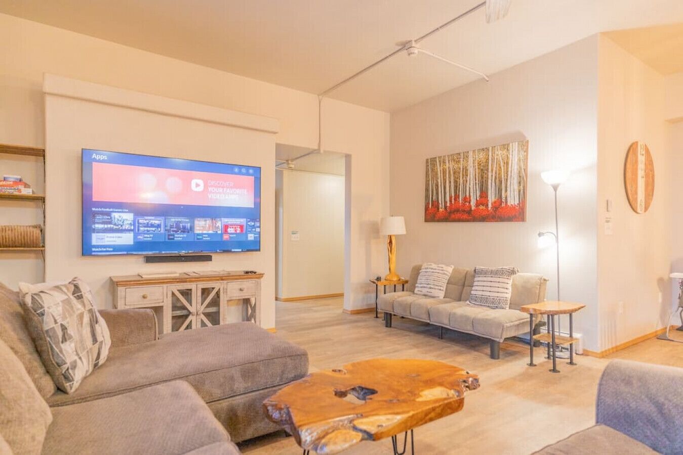 Un salon avec un téléviseur à écran plat, un canapé, une table basse et un tableau accroché au mur.