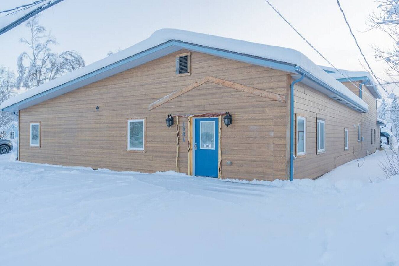 Een houten gebouw met een blauwe deur, ramen en een met sneeuw bedekte kap.