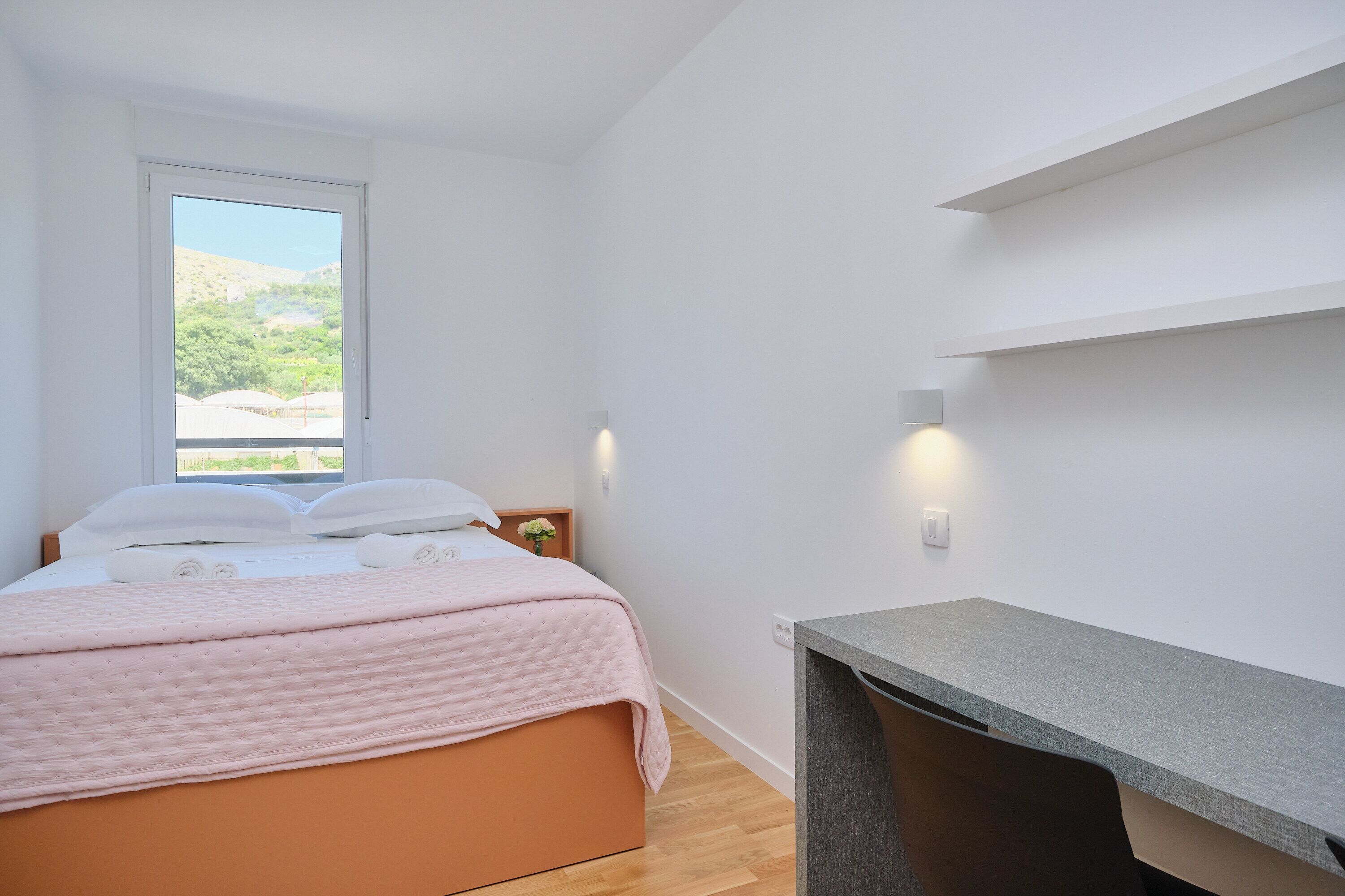 A bedroom with a bed, a desk, and a window.