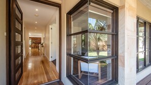 A modern interior with a wooden floor, a glass door leading to a patio, and a view of a garden. - Luxury and Style on Pasadena with large spa (Rye)
