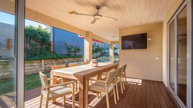 An outdoor patio with a wooden table and chairs, a ceiling fan, and a TV mounted on the wall. - Luxury and Style on Pasadena with large spa (Rye)
