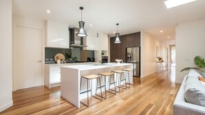 A modern kitchen with a central island, bar stools, and a dining area. - Luxury and Style on Pasadena with large spa (Rye)