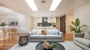A modern living room with a grey sofa, a coffee table, and a dining area with a wooden table and chairs. - Luxury and Style on Pasadena with large spa (Rye)