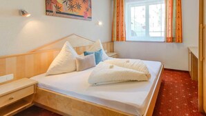 Une chambre d’hôtel avec un lit, une table de chevet, une fenêtre avec des rideaux et un tableau au mur.