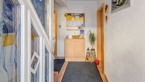 Un couloir avec une armoire en bois, un tableau d’affichage et une petite plante.