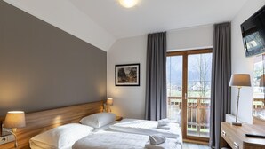 Una camera d'albergo con un letto, lampade sui comodini, una TV e una finestra con tende.