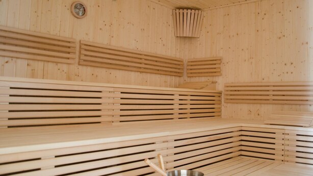Una sauna con panche in legno e un catino di metallo.